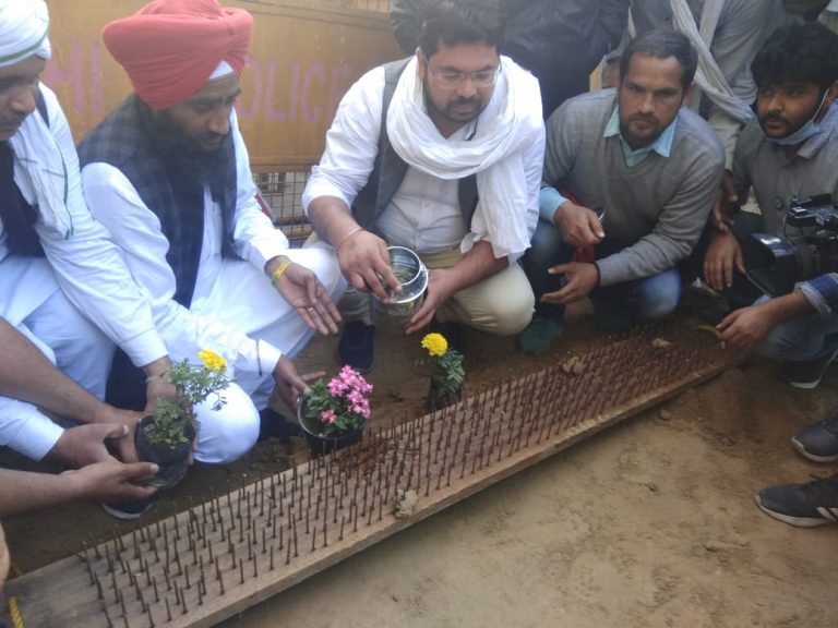 Agitated farmer leaders plant flower saplings to respond iron thorns panted by Delhi Police